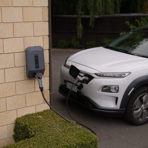A white electric car charging at a station in Christchurch, New Zealand, showcasing modern eco-friendly transportation.